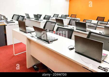 Empty computer classroom with monitors on top of table Stock Photo
