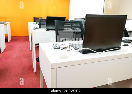Empty computer classroom with monitors on top of table Stock Photo