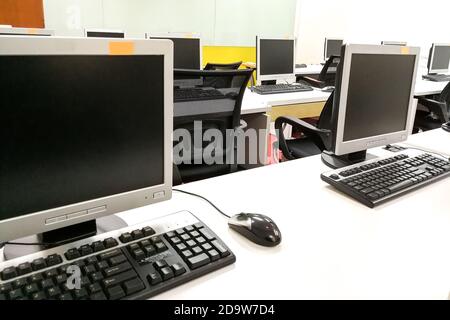 Empty computer classroom with monitors on top of table Stock Photo