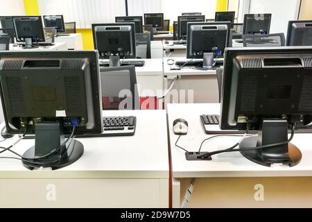 Empty computer classroom with monitors on top of table Stock Photo