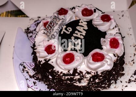 White and chocolate birthday cake with red cherry on top. Stock Photo