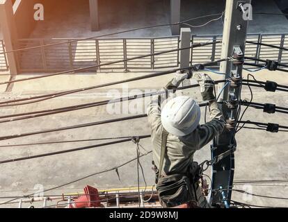 Electricians are climbing on electric poles to install power lines. Stock Photo