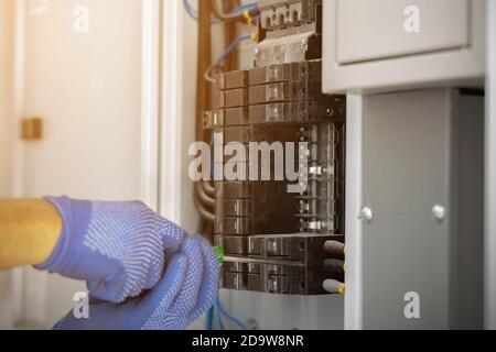 Electrician is using a screwdriver to install the breaker in the electrical control cabinet of the building. Stock Photo