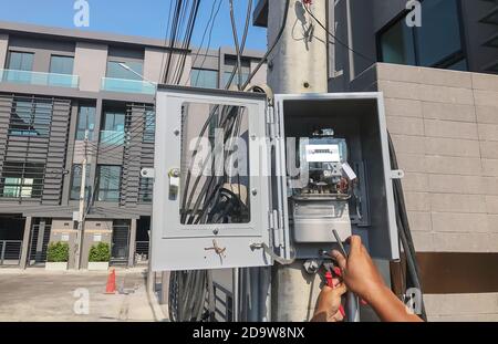 Electrician is setting up a meter to measure the electricity consumption in the box on the pole. Stock Photo