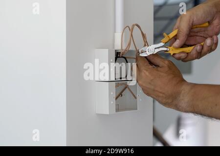 Technicians are using pliers to cut wires to install plugs and switches on the front door. Stock Photo