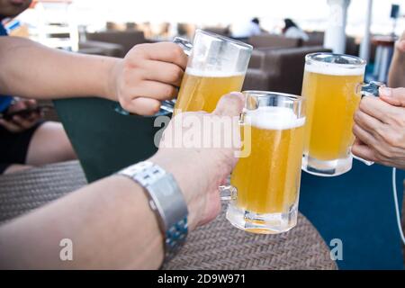 Three person knocking beer glasses to toast in celebration Stock Photo