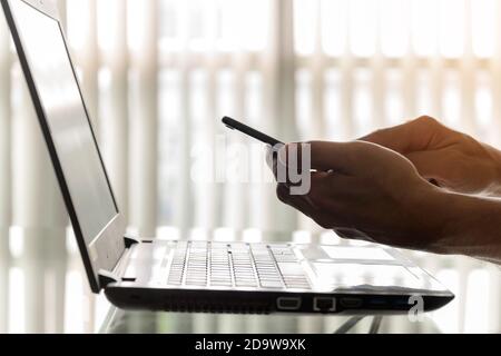 Closeup hands of businessmen are using smartphones and laptops in the office. Stock Photo