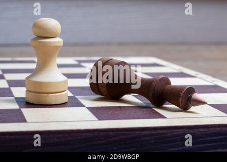 The end of the chess game, the white pawn defeated the dark king. The fallen chess king as a metaphor for the fall of power. Business concept copy space, selective focus Stock Photo