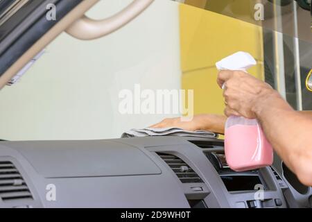 Cleaning staff is using a varnish and microfiber cloth to clean the interior of the car, concept for car care industry. Stock Photo