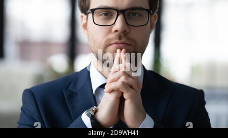 Close up head shot thoughtful young businessman looking at camera. Stock Photo