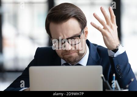 Stressed 30s businessman irritated by bad computer work. Stock Photo