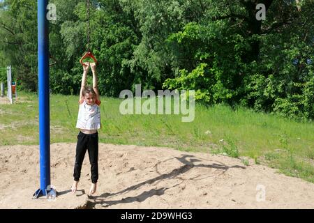Kid on rotating rope swing around central pole in park Stock Photo