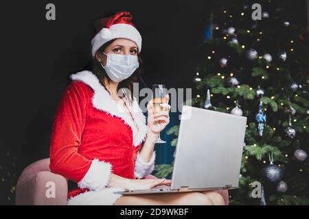A beautiful girl meets Christmas and New Year through a video call with friends. Quarantine. Self-isolation. Coronavirus 2020. Stock Photo