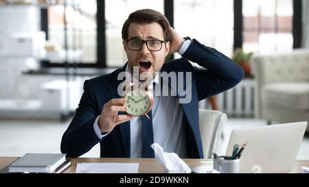 Stressed young businessman holding clock in hands. Stock Photo