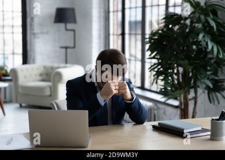 Stressed young ceo manager sitting at table with head down. Stock Photo