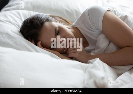 Depressed female lying at bed spending bad night alone