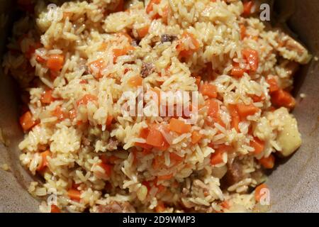 Cooked pilaf in cauldron on coals in backyard Stock Photo
