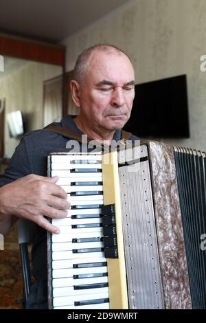 Senior man playing the accordion at home Stock Photo