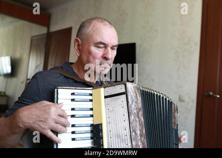 Serious man playing the accordion at home Stock Photo