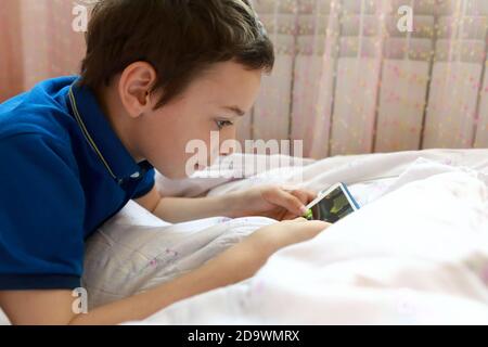 Child playing in smartphone on bed at home Stock Photo