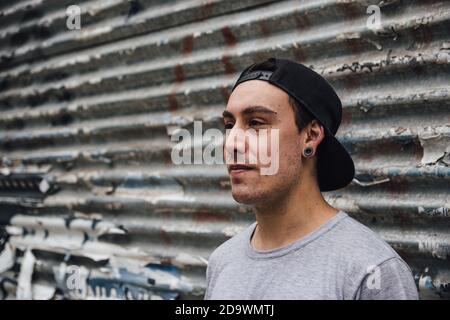 Closeup shot of a cool young man posing in front of an old garage wall Stock Photo
