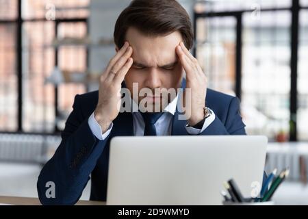 Young 30s male company worker employee having strong headache. Stock Photo