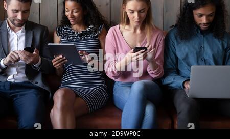 Group of diverse millennial men and women communicating by gadgets Stock Photo