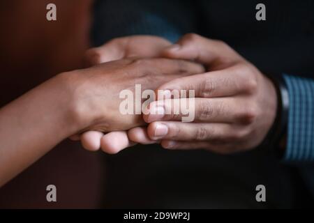 Male hands covering palm of mixed race female expressing care Stock Photo
