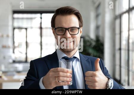 Happy young employee holding glass of water in hands. Stock Photo