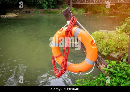 A rubber ring with a rope hanging on a wooden pole along the river was prepared for rescue. Stock Photo