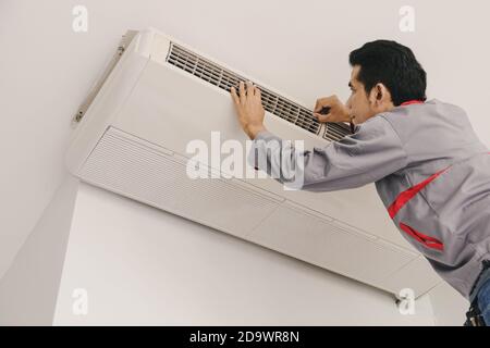 Air conditioner repairers are checking and repair air hanging on the wall. Stock Photo