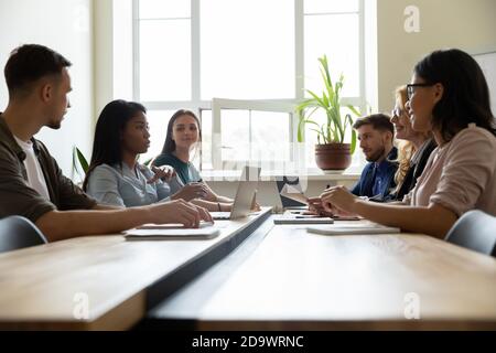Diverse business team sitting in meeting room discussing project Stock Photo