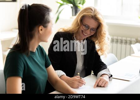 Satisfied older and younger female business partners concluding agreement Stock Photo