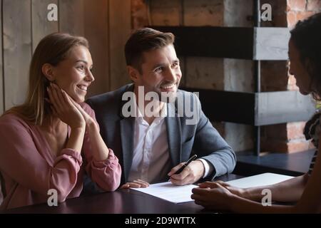 Millennial couple apartment buyers signing papers on meeting with agent Stock Photo