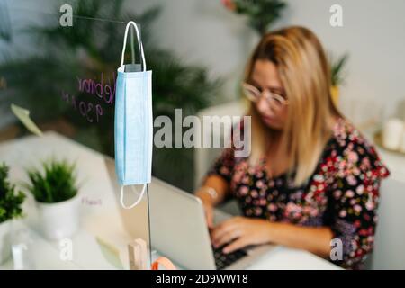 Young woman working in a office with protective mask and social distance Stock Photo
