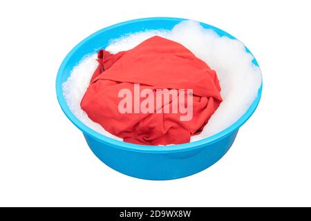 Red shirt soaked in washing powders in the plastic basin. Stock Photo
