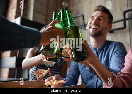 Diverse millennial friends making toast for meeting raising beer bottles Stock Photo
