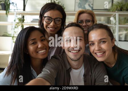 Happy laughing team of diverse colleagues taking selfie in office Stock Photo