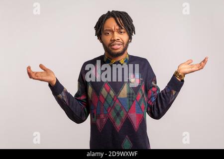 I dont know. Confused african man with beard and dreadlocks throwing up his hands, puzzled, uncertain, cant find answer to question. Indoor studio sho Stock Photo