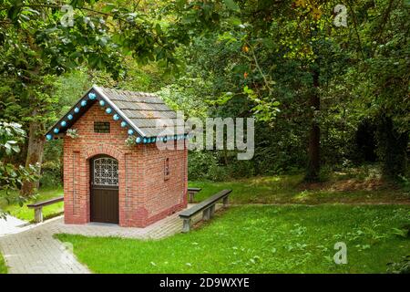 Kortenaken, Flanders, Belgium - July 9 2017 : small brick chapel 'Onze-Lieve-Vrouw van de Dellebron' decorated with blue paper flowers, surrounded by Stock Photo