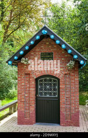 Kortenaken, Flanders, Belgium - July 9 2017 : small brick chapel 'Onze-Lieve-Vrouw van de Dellebron' decorated with blue paper flowers, surrounded by Stock Photo