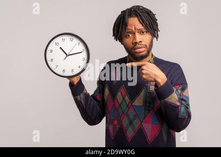 Time management. Displeased man showing clock to laptop screen, having ...