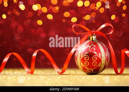 Red Christmas ball on red glitter background with gold lights Stock Photo
