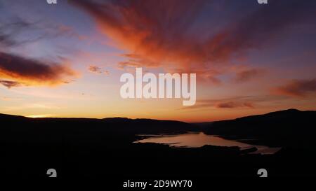Stunning panorama view over reservoir Bin el Ouidane Dam with water reflection and beautiful colored dramatic sky with orange clouds near Beni Mellal. Stock Photo