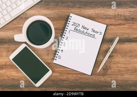 2021 New Year resolution text on notepad with cup of coffee, smart phone, pen Stock Photo