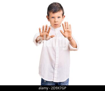 Cute blond kid wearing elegant shirt moving away hands palms showing refusal and denial with afraid and disgusting expression. stop and forbidden. Stock Photo