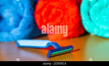 The razor lies on mirrored bath table against the background of three towels Stock Photo