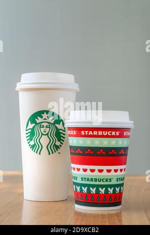 Chiang Mai, Thailand - 07 November 2020 - Two Starbucks coffee take home paper cup in two different sizes, Grande and Tall, sit on a wooden table on N Stock Photo
