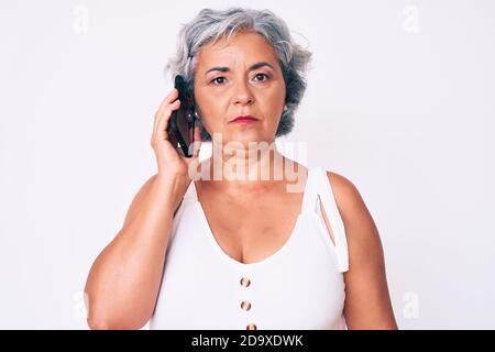 Senior hispanic grey- haired woman having conversation talking on the smartphone thinking attitude and sober expression looking self confident Stock Photo