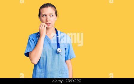 Young beautiful blonde woman wearing doctor uniform and stethoscope looking stressed and nervous with hands on mouth biting nails. anxiety problem. Stock Photo